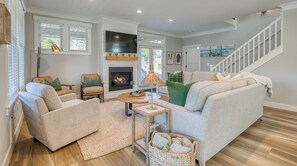 Una sala de estar con chimenea, sofá, sillón y una escalera.