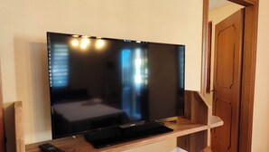 Un televisor de pantalla plana montado en una consola de madera con un control remoto.