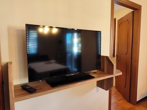 Ein Flachbildfernseher an einer Holzkonsolle, inklusive Fernbedienung.