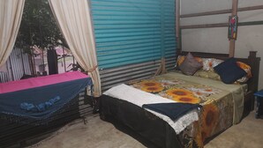 A room with a bed, a hammock, and a window with curtains. - Apartment with access to the beach, a place to stroll beautiful experience. (Quepos)
