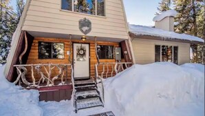 A cabin with a wooden exterior, a front door, and a small porch with a railing. - Winterfell Mountain Retreat (Island Park)