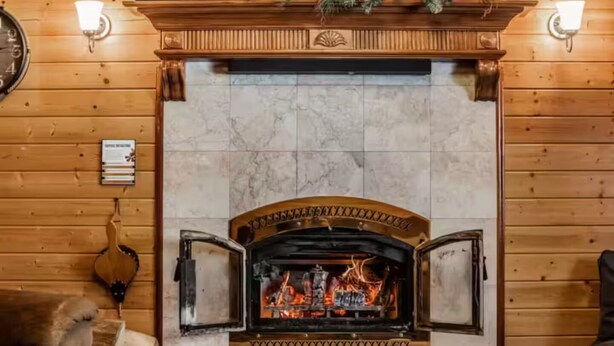 A fireplace with a marble surround, flanked by wooden walls and two wall-mounted lights. - Winterfell Mountain Retreat (Island Park)