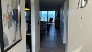 A hallway with a view to a balcony, a framed abstract painting, and a door labeled '719'. - ENJOY SUNRISES, SUNSETS FROM THIS BEAUTIFUL 7TH FLOOR HUTCHINSON ISLAND CONDO!! (Jensen Beach)