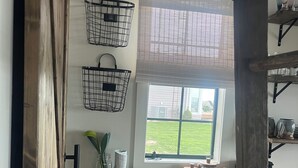 Una cocina con ventana, estantes de madera y cestas colgantes.