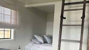 Un dormitorio estilo loft con cama, escalera, sofá y ventana con persianas.