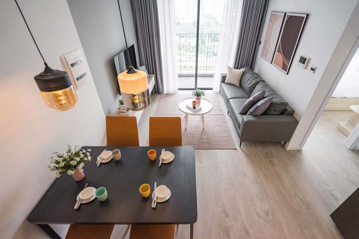 A modern living room with a dining area, a sofa, and a view of the outdoors.