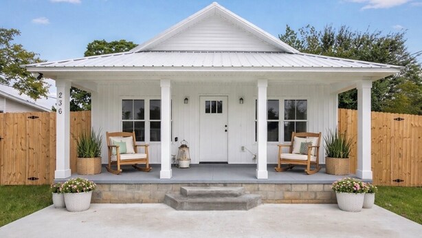 A white house with a porch, two wicker chairs, and potted plants. - North Boulevard Breeze Stylish New Home Near Beaches & Historic District (St. Augustine)