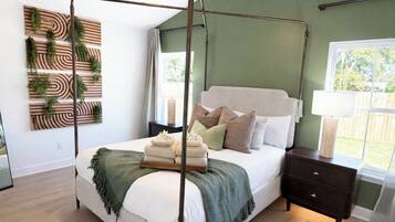 Un lit à baldaquin avec un cadre en bois, une table de chevet, une petite table et une plante fixée au mur.