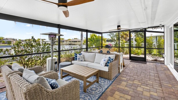 A covered outdoor area with wicker furniture, a wooden table, and a ceiling fan. - Canalfront 3BR Heated Pool With Boat Lift (Punta Gorda)
