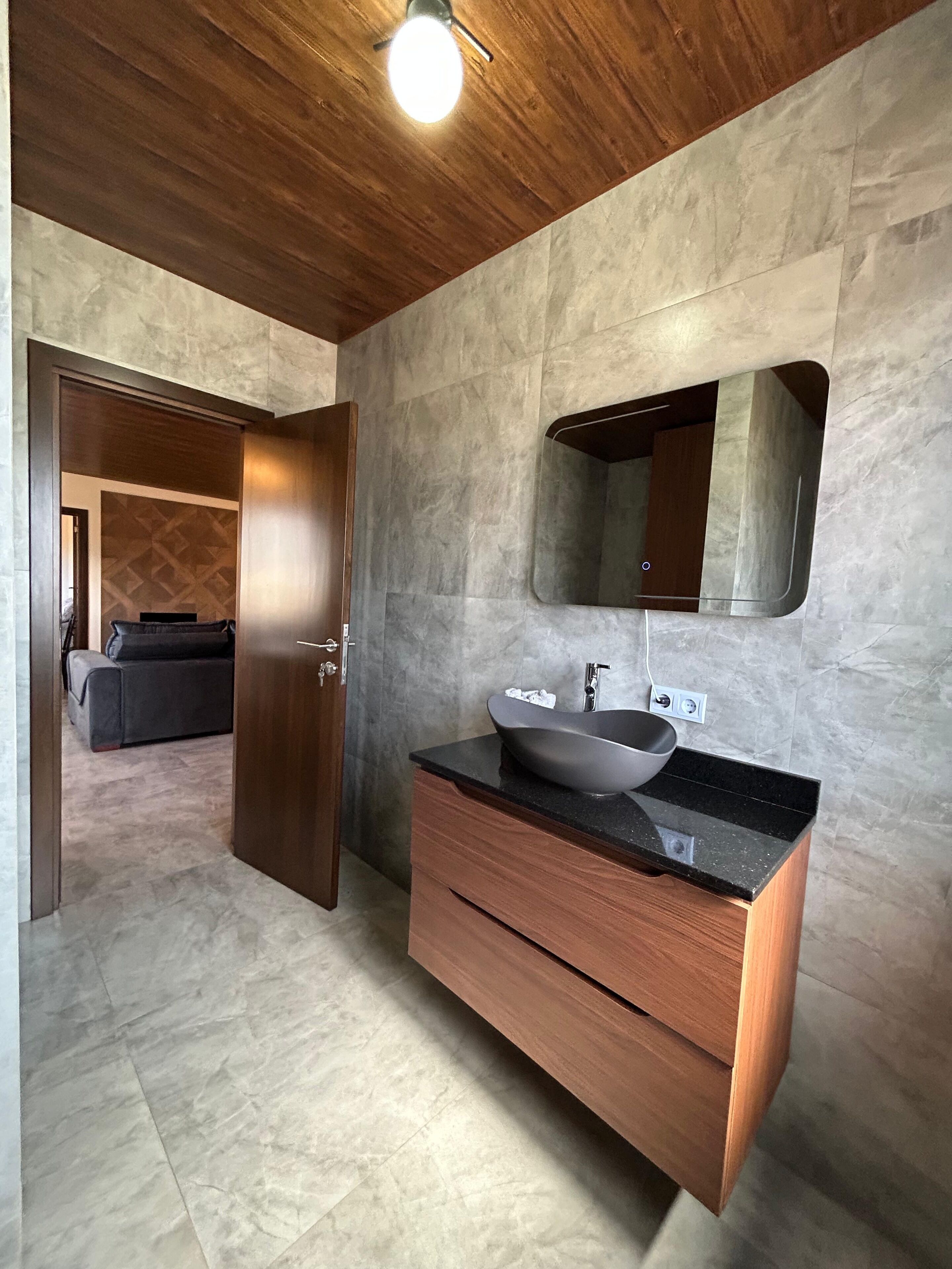 Une salle de bain moderne avec un meuble-lavabo en bois, un vasque et un grand miroir.