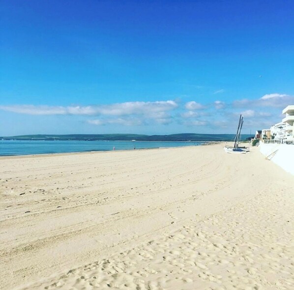 A beach with a clear sky, a sandy shore, and a building with a white facade.