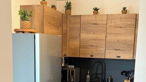 Una cocina compacta con armarios de madera, un refrigerador de acero inoxidable, un microondas y un lavamanos.