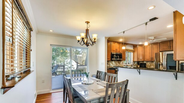 A modern kitchen with wooden cabinets, a dining table with chairs, and a chandelier.