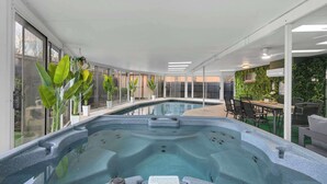 A modern indoor pool area with a hot tub, surrounded by large windows and indoor plants. - Indoor Pool & Hot Tub Near AT&T Stadium (Irving)