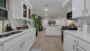 A modern kitchen with white cabinetry, gold handles, and a central island. - Indoor Pool & Hot Tub Near AT&T Stadium (Irving)