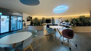 A modern waiting area with a round table, chairs, sofas, and potted plants. - Nordic Home Bliss With Marimekko Moments (Helsinki)