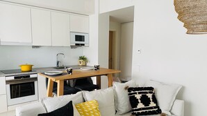 A modern kitchen with white cabinets, a microwave, and a yellow pot on the stove. - Nordic Home Bliss With Marimekko Moments (Helsinki)