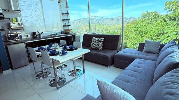 A modern living space with a kitchen, dining area, and seating area with a view of mountains. - Beautiful apartment with a private Jacuzzi (Jal.)