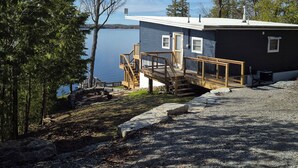 Une cabane dotée d’une terrasse en bois et offrant une vue sur un lac.