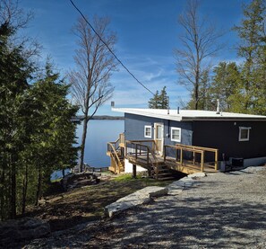 A cabin with a wooden deck and a view of a lake. - Lakefront Cottage on Private Road (Kawartha Lakes)