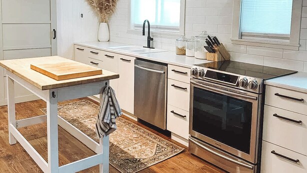 Una cucina moderna con mobili bianchi, un forno in acciaio inossidabile e un tavolo di legno.