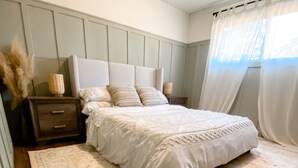 Una camera da letto con un letto grande, un comodino, una lampada e una finestra con tende.