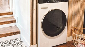Una lavatrice e asciugatrice combinate LG in una cucina moderna con pannelli in legno e un tappeto decorato.