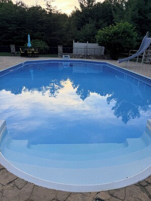 Una piscina rectangular con borde blanco, rodeada de un patio de piedra.