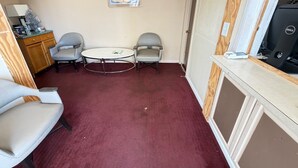 A small room with a round table, two chairs, a desk with a computer, a cabinet, and a framed picture on the wall. - Deluxe Inn (Mauldin)