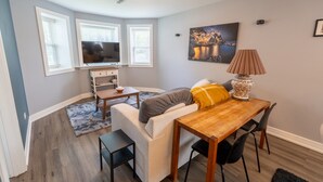 A modern living room with a sofa, dining table, and TV. - 2 Bedroom apartment free parking near transit (Chicago)