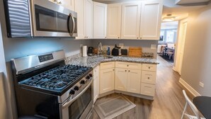 A modern kitchen with white cabinets, stainless steel appliances, and a granite countertop. - 2 Bedroom apartment free parking near transit (Chicago)