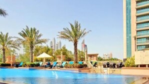 A swimming pool with lounge chairs and palm trees, surrounded by modern buildings. - Vibrant 2 Bed l The Greens l Family Retreat (The Greens)
