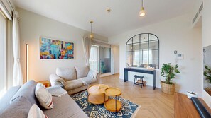 A modern living room with a sofa, coffee table, and a dining area with a bench. - Vibrant 2 Bed l The Greens l Family Retreat (The Greens)