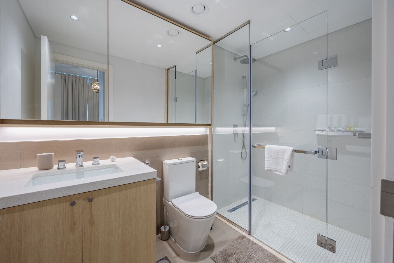 Une salle de bain moderne avec une douche à parois de verre, un meuble-lavabo en bois et un grand miroir.