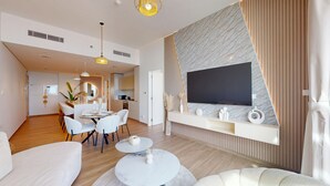 Una sala de estar moderna con comedor, un televisor montado en la pared y una zona de estar acogedora.