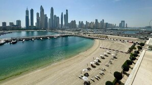 A coastal cityscape with a marina, sandy beach, and high-rise buildings. - Modern 1 Bed l Private Beach l Pool, Gym Access (Emaar Beachfront)