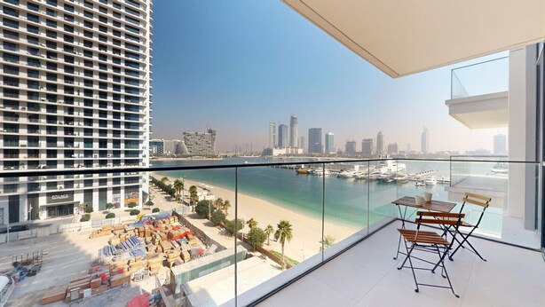 A high-rise building with a balcony overlooking a beach and marina. - Modern 1 Bed l Private Beach l Pool, Gym Access (Emaar Beachfront)