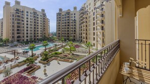 A high-rise residential building with multiple balconies, a swimming pool, and landscaped gardens. - Luxury Living 1 Bed l Pool View l Burj Al Arab (Madinat Jumeirah Living)