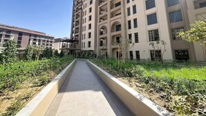 A multi-story residential building with balconies, a central pathway, and surrounding greenery. - Luxury Living 1 Bed l Pool View l Burj Al Arab (Madinat Jumeirah Living)