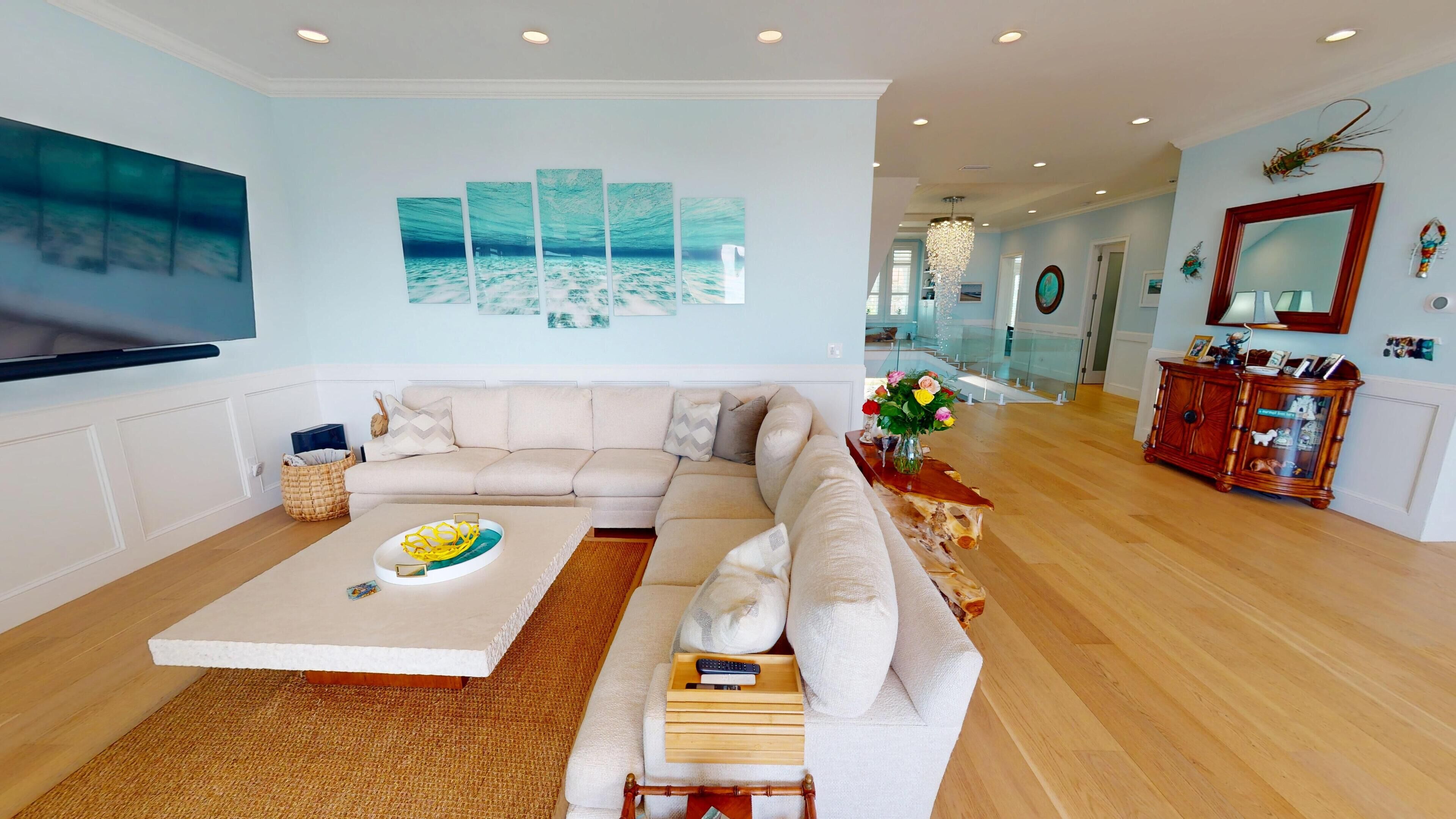 A spacious living room with a large sectional sofa, a flat-screen TV, and a dining area with a table set for two.