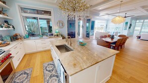 A spacious kitchen with a large island, a dining area with a wooden table, and a view of the outdoors.