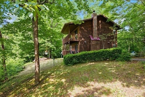 A log cabin with a balcony, surrounded by dense greenery. - Unobstructed Smoky Mountain Views, Hot Tub, Pigeon Forge (Pigeon Forge)