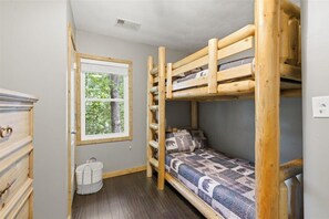 A bunk bed room with a window, a dresser, and a basket. - Above It All | Hot Tub + Smoky Mtn Views - Holiday Home (Pigeon Forge)