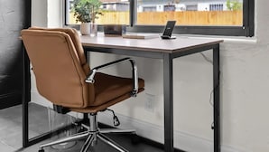 Een moderne kantoorruimte met een bureau, stoel en airconditioningsystemen.