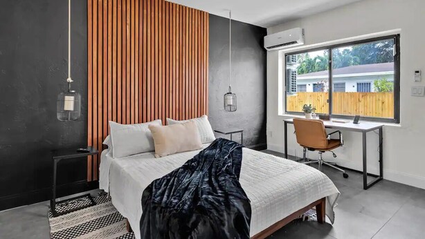 Een moderne slaapkamer met een bed, bureau en groot raam.