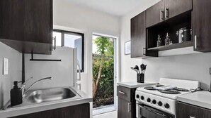 Een moderne keuken met donkerhouten kasten, een roestvrijstalen spoelbak en een witte kookplaat.