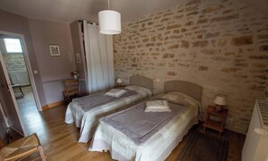 A bedroom with two beds, a stone wall, a wooden floor, a white lamp, and a radiator. - Ideal for vacations with family or friends! Beautiful, spacious gîte on the water's edge! (Bussy-le-Grand)