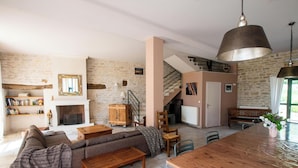A spacious living room with a fireplace, a staircase, and a dining area.