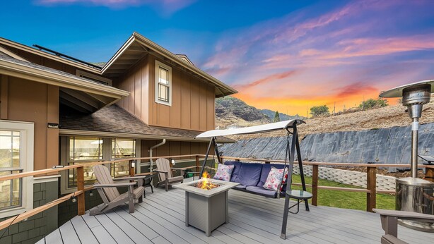 A deck with a fire pit, outdoor seating, and a view of the mountains.