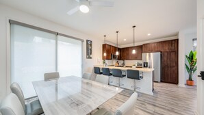 A modern kitchen with wooden cabinets, a stainless steel refrigerator, and pendant lighting.